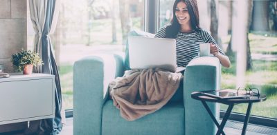 a woman sitting on a couch with a laptop.