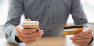 a man holding a credit card and a cell phone.
